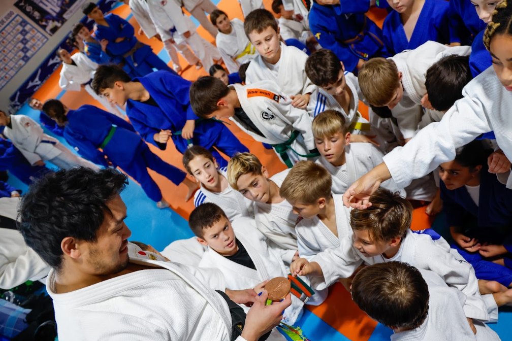 Ryunosuke Haga enseñando su medalla olímpica a un grupo de niños en el tatami